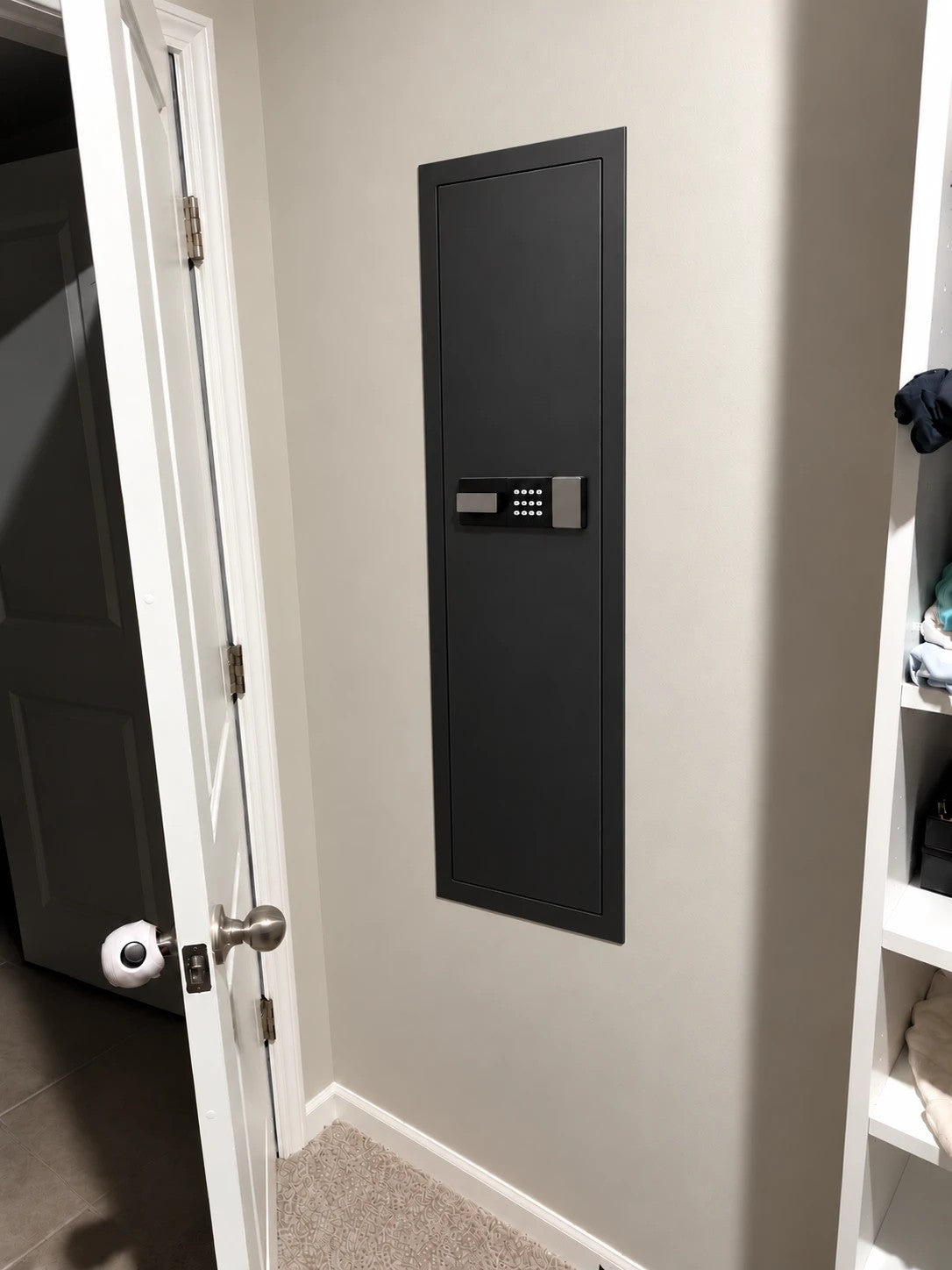 SLATE M in-wall gun safe in black, installed flush in a closet wall beside the door
