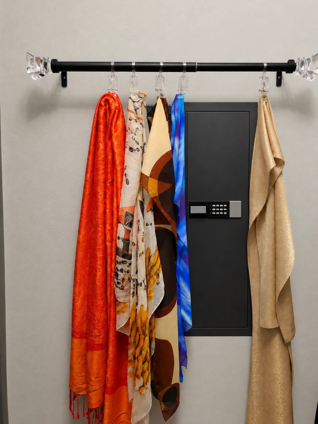 SLATE M in-wall gun safe in black, partly hidden behind scarves on a wall rail