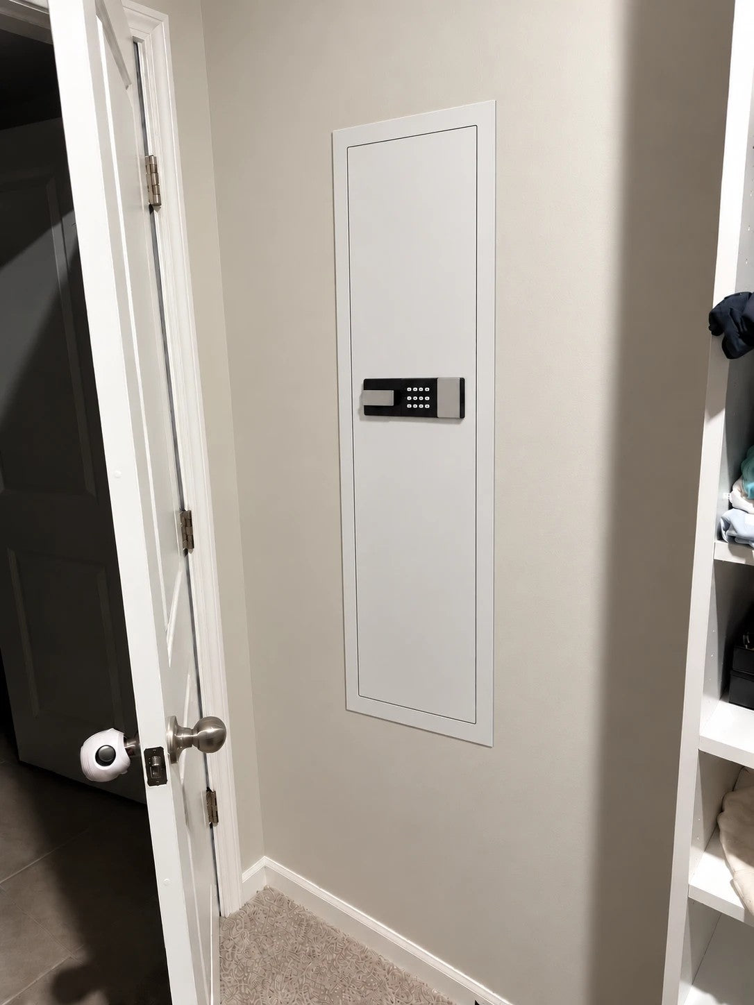 SLATE M in-wall gun safe in white, installed flush in a closet wall beside the door