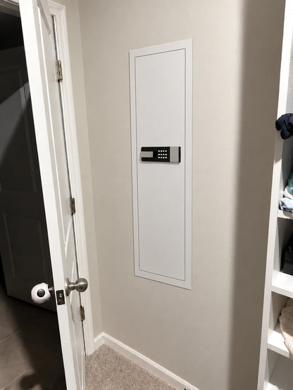 SLATE M in-wall gun safe in white, installed flush in a closet wall beside the door